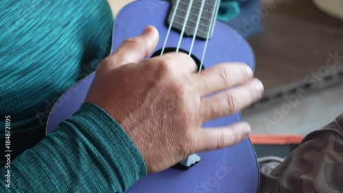 Ukulele playing music, male hands close-up creating melodic sounds
