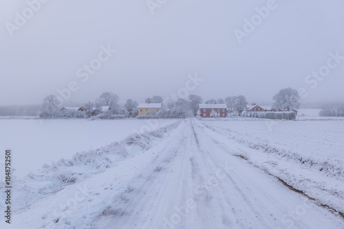 Farm barn and house in a cold winter landscape with snow and frost