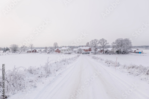 Farm barn and house in a cold winter landscape with snow and frost