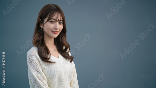 白のレース風ニットを着た美しい女性が、カメラにやさしく微笑んでいる