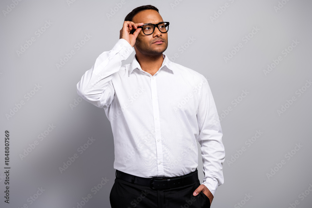 Obraz premium Young handsome businessman in white shirt and glasses stands in a professional office looking thoughtful and confident