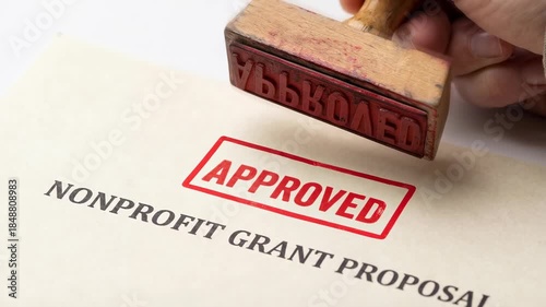 Brainstorming nonprofit grant proposal document with hand stamped paper for funding approval supporting charitable projects and community initiatives