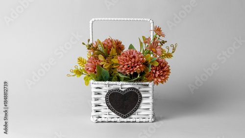 Beautiful plastic flowers decoration in basket on grey background