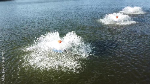 Aerial view of water aerators creating circular splashes on a green water surface. Abstract pattern representing water treatment, environmental management, sustainability, and clean water concepts.