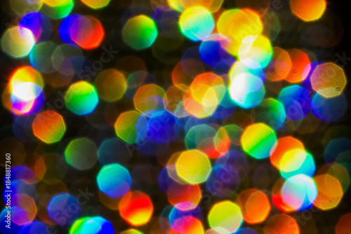 Abstract bokeh-style background with multicolored lights of red, green, blue, yellow, etc., creating a festive effect of blurred glitter.