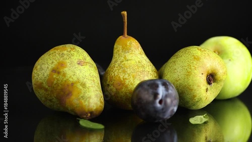Ripe pears and plums on a black background