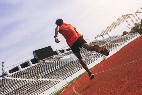 Fit young man running sprinting at the racetrack. Fit runner fitness runner during outdoor workout at racetrack.