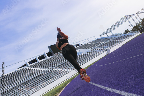 Silhouette of fit young woman running sprinting at the racetrack. Fit runner fitness runner during outdoor workout at racetrack.