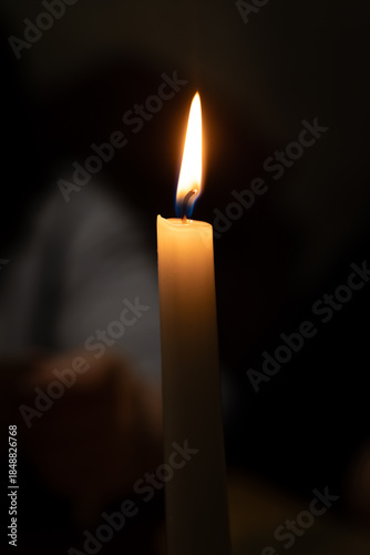 Close-up of a lit candle against a dark, blurred background, creating a warm and serene atmosphere suitable for various themes and designs.