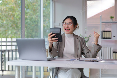 Cuadro en lienzo Happy young businesswoman showing excitement after calculating finances and achi