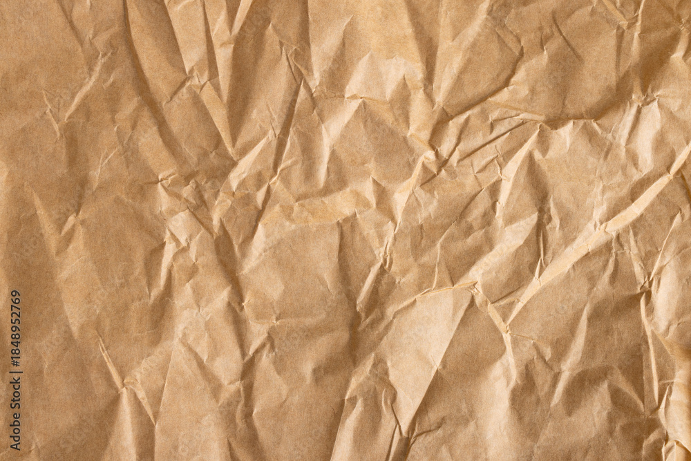 Obraz premium Close-up macro view of a wrinkled brown paper surface,Brown crumpled paper page macro close up view,brown wrinkled paper texture and background. top view
