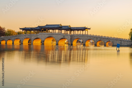 On the morning of December 8, 2025, golden sunlight shone through an ancient covered bridge over Jinji Lake in Suzhou, China