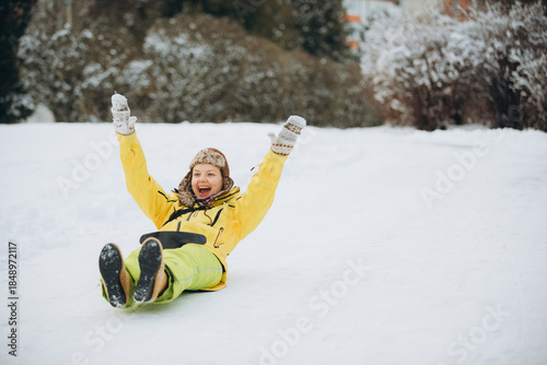 Woman sliding down snowy hill celebrating winter fun