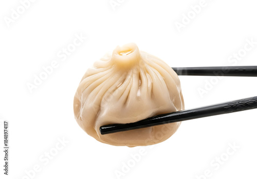 Delicate soup dumpling held by chopsticks against a black background