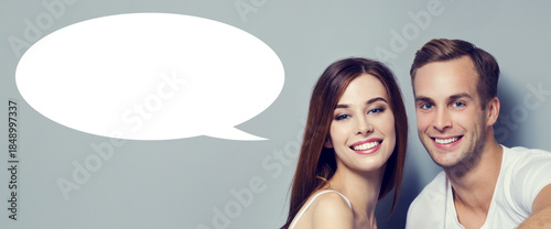 Love, relationship, lovers, romantic date concept - happy cute young couple. Portrait of close stand man woman, isolated grey gray background with white empty mockup speech bubble, free ad text space