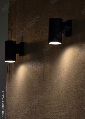 Fotografija Black modern sconce lights casting warm light and shadows on an interior texture