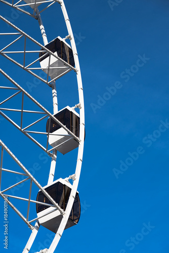 Vertical shot of a Ferris wheel cabin under the clear blue sky .  Copy space