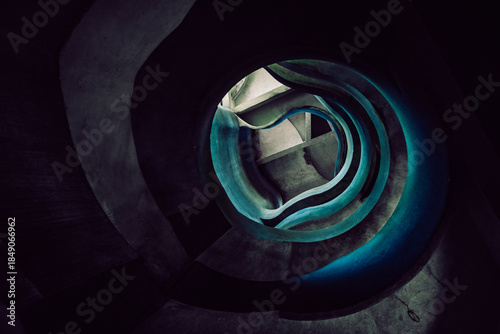 View of a winding staircase, a dark vortex of steps illuminated with an eerie blue glow, descending into the unknown, Crevarska Strana, Sisak-Moslavina County, Croatia.