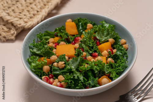 Seasonal Kale Salad with Roasted Pumpkin, Chickpeas, and Pomegranate on Beige Background