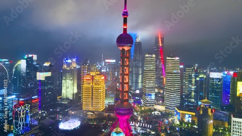 Aerial panoramic view of the Oriental Pearl Tower and numerous modern, brightly illuminated skyscrapers defining the urban skyline of Shanghai, China.