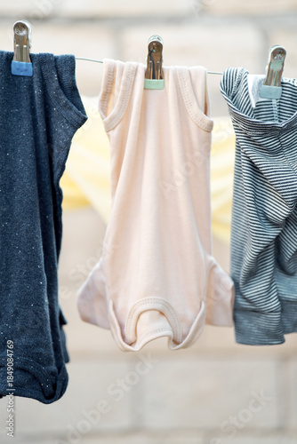 Baby bodysuits and clothes hanging on a clothesline