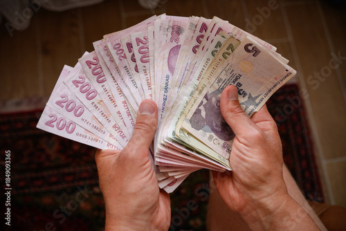 Fototapeta Naklejka Na Ścianę i Meble -  Man holding Turkish lira banknotes indoors while counting Turkish national currency banknotes. Concepts of savings, finance, cash payments, inflation