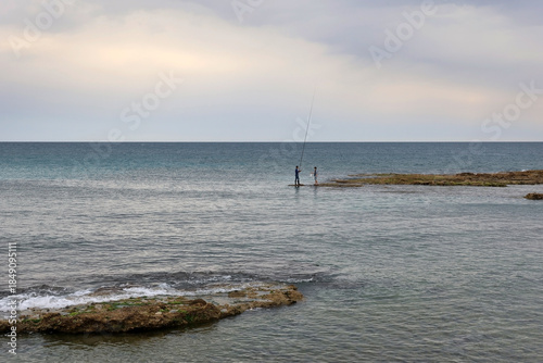 Fishermen on a Rock Formation in Calm Sea