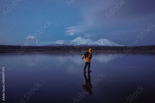 A Man on a Frozen Lake with a View of Kamchatka Volcanoes
