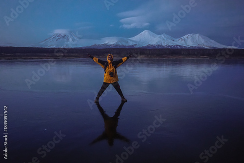 A Man on a Frozen Lake with a View of Kamchatka Volcanoes