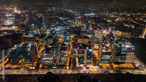 Aerial view of the gleaming cityscape, where warm lights flicker against the dark canvas of night, illuminating the modern architecture, Hyderabad, Telangana, India.