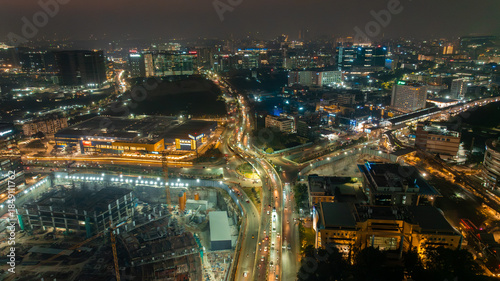 Aerial view of a vibrant cityscape with illuminated buildings, highways, and ongoing construction projects casting a warm glow, Hyderabad, Telangana, India.