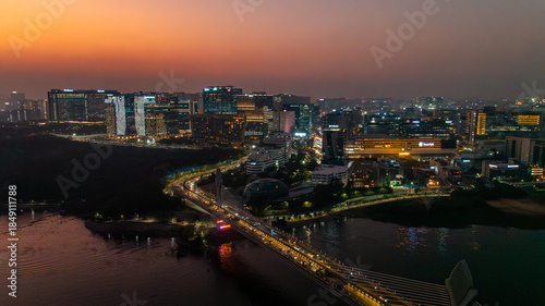 Wallpaper Mural Aerial view of the illuminated Durgam Cheruvu bridge stretching across the tranquil waters, reflecting the vibrant cityscape against the dusky horizon, Hyderabad, Telangana, India. Torontodigital.ca