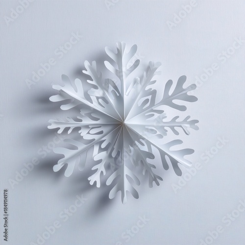 Intricate white paper snowflake on soft light gray background