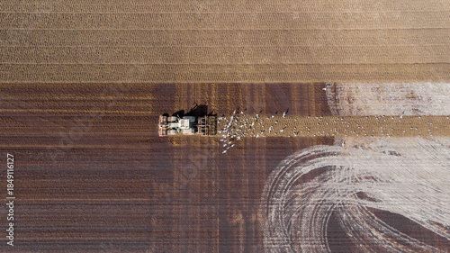 Aerial view of a tractor tilling the land, churning up the soil in stark contrast to the untouched earth, Agriculture, North Holland, Netherlands.