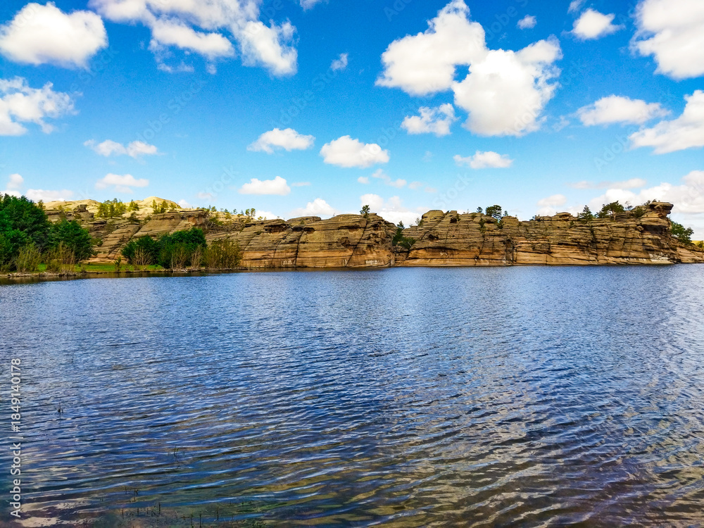 Fototapeta premium tranquil lake in Bayanaul, Kazakhstan. Layered rock formations along the shoreline. Untamed charm of this Kazakh region. For travel brochures, nature documentaries, eco-tourism websites.
