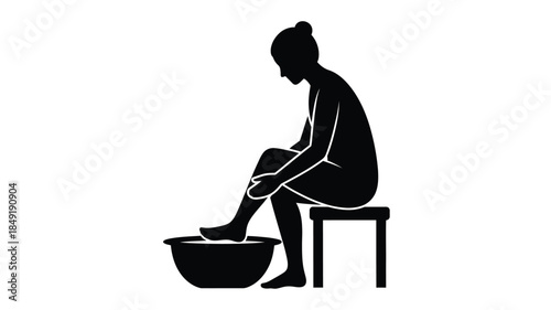 A woman seated soaking feet in a basin black silhouette