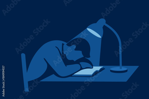 Man sleeping at desk under lamp with book in dark room