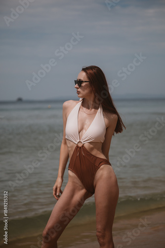 young woman in a swimsuit on the beach and sunglasses