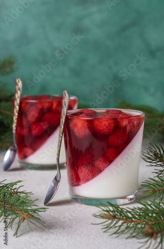 Festive Dessert Panna Cotta with strawberry in two glasses on green background