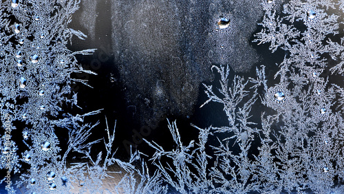 the image of frost on the glass. Subzero temperatures outside. Crystals of frozen water on glass. Beautiful pattern of frost on the window glass. ice, for text or image as background