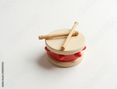 Red toy drum with drumsticks lying on white background