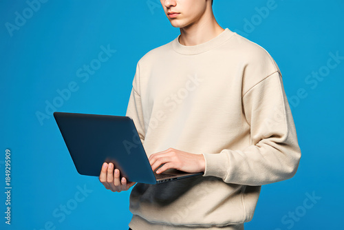 Full body portrait of nice young man hand hold laptop wear beige sweatshirt isolated on blue color background