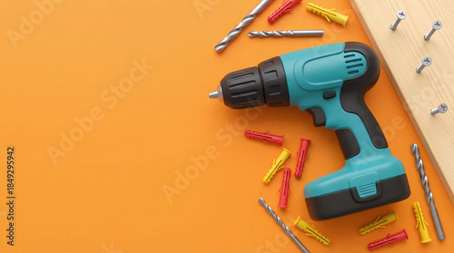 Fototapeta Naklejka Na Ścianę i Meble -  Electric power drill with screws and wood plank on orange