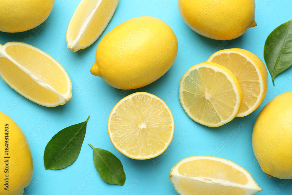 Fototapeta premium Fresh ripe lemons and leaves on light blue background, flat lay