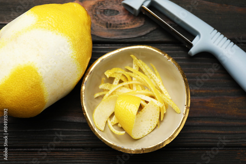 Tableau sur toile Lemon zest, fresh fruit and peeler on wooden table, flat lay