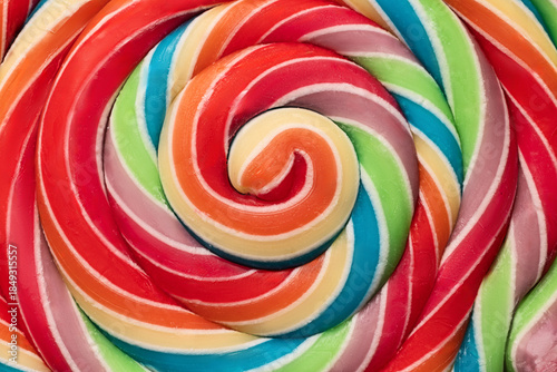 Fotografie Colorful rainbow lollipop swirl on wooden stick as food color background