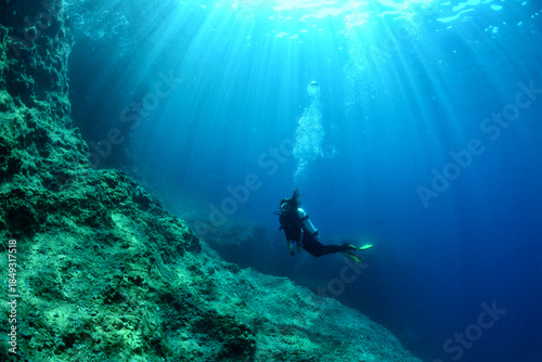 Quadro su tela Silhouette of a scuba diver underwater, emphasizing human scale against the vast marine environment