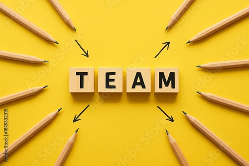 Vibrant yellow background showcases word TEAM spelled out with wooden blocks, surrounded by pencils pointing towards, symbolizing unity and collaboration. Collective effort, teamwork and cooperation