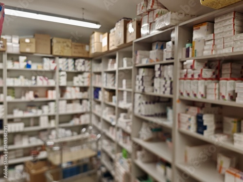 Blurred view of a pharmacy warehouse filled with stocked boxes of medicinal products and vitamins, illustrating pharmaceutical supply chain, inventory management, and healthcare distribution system