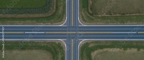 Aerial symmetrical four way rural highway intersection with green fields